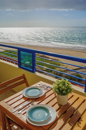 Ein Tisch gedeckt mit Geschirr und Besteck, mit Blick auf einen Strand und das Meer.