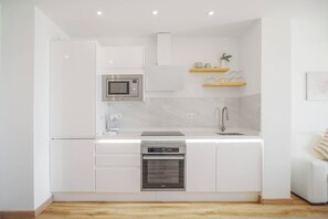 Eine moderne Küche mit weißen Schränken, einer eingebauten Mikrowelle, einem Edelstahlbackofen und einem Spülbecken mit Armatur.