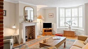 A living room with a fireplace, television, and seating area. - Aldeburgh - spacious 3 bed period house on High St (Aldeburgh)