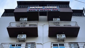 A building with multiple balconies, air conditioning units, and a sign that reads 'Hotel Dibyansh Premium.' - HOTEL DIBYANSH PREMIUM (Bhubaneshwar)