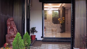 A tiled entrance area with potted plants and a wooden statue. - HOTEL DIBYANSH PREMIUM (Bhubaneshwar)