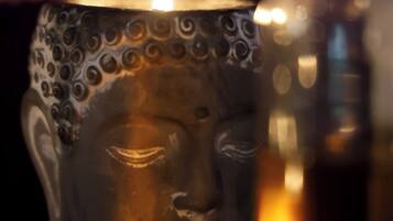 A candle in a decorative holder with a Buddha-like face.