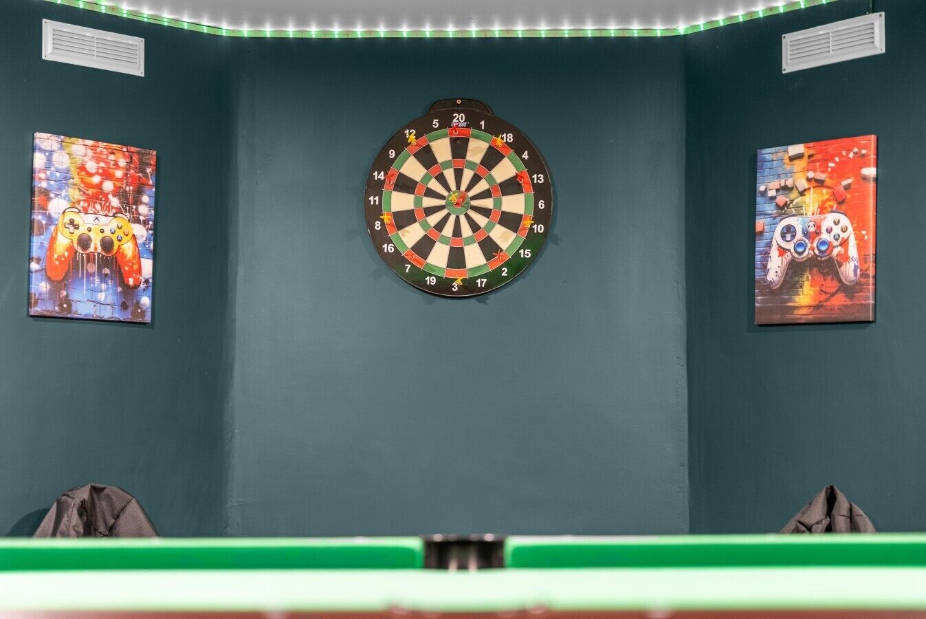 A dartboard mounted on a wall with two gaming posters on either side.