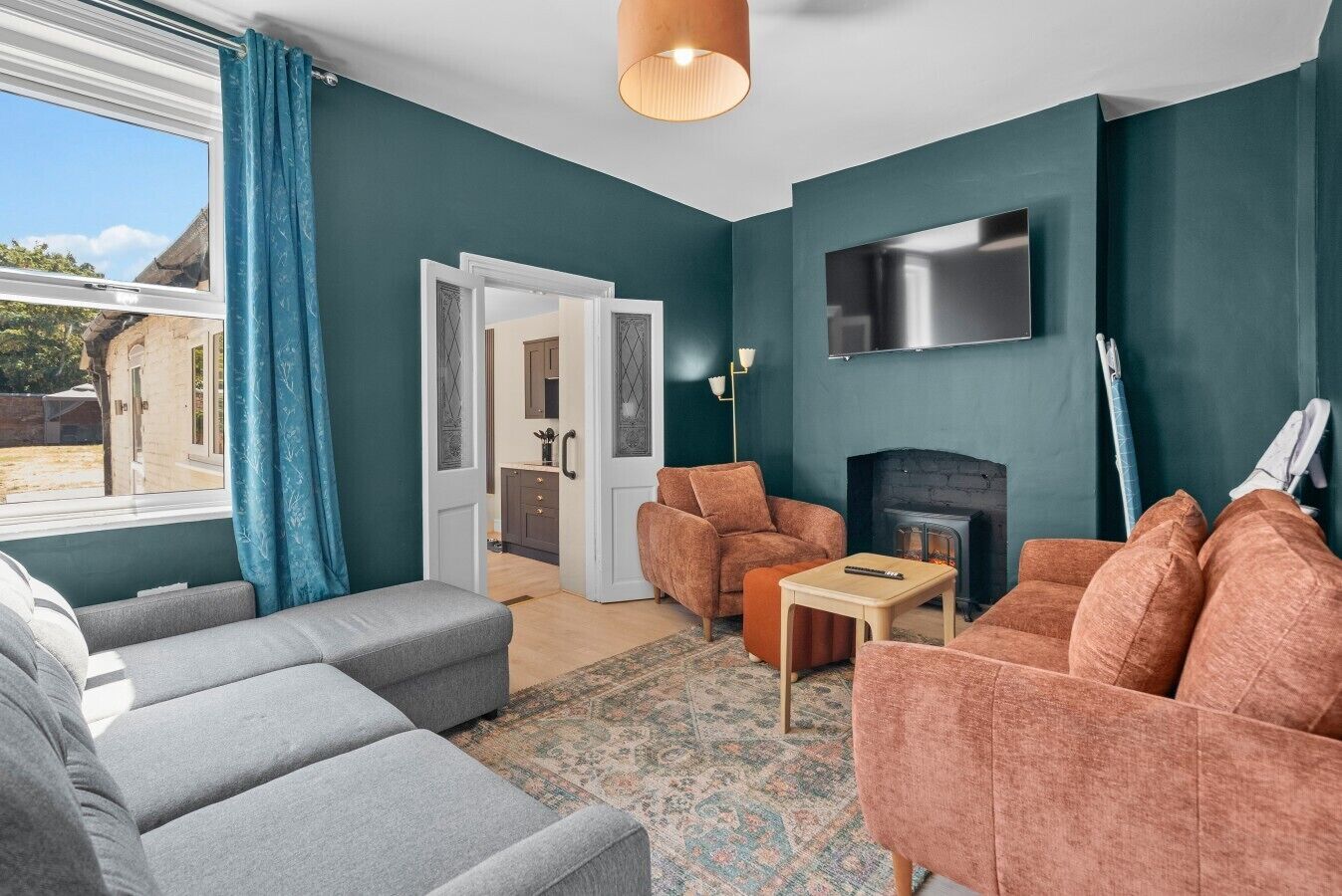 Un salon aux murs de couleur turquoise, avec une cheminée, un téléviseur fixé au mur et un canapé.