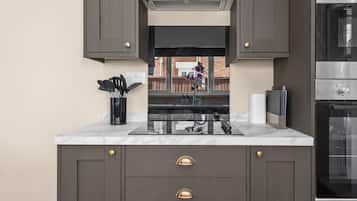 A modern kitchen with dark cabinetry, a stainless steel oven, and a marble countertop.