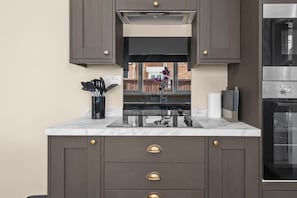 Een moderne keuken met donkere kastjes, een roestvrijstalen oven en een marmeren aanrecht.