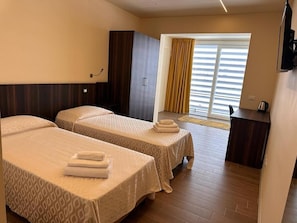 A hotel room with two beds, a desk, and a window with curtains. - KRINO' HOTEL&CAFE' (Augusta)