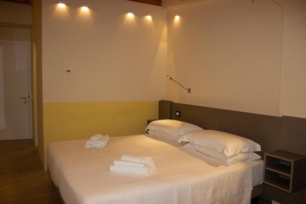 Habitació d'hotel amb un llit, taules de nit i llums penjades a la paret.