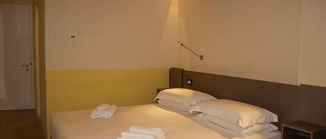 Une chambre d’hôtel avec un lit, des tables de chevet et des lampes fixées au mur.