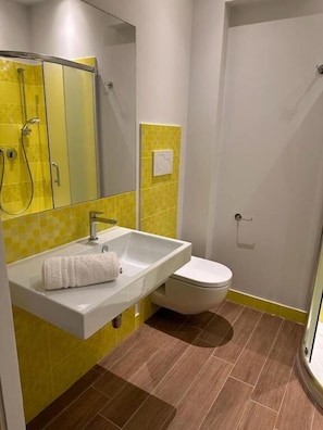 Une salle de bain équipée d’un lavabo, d’un miroir, de toilettes et d’une douche.