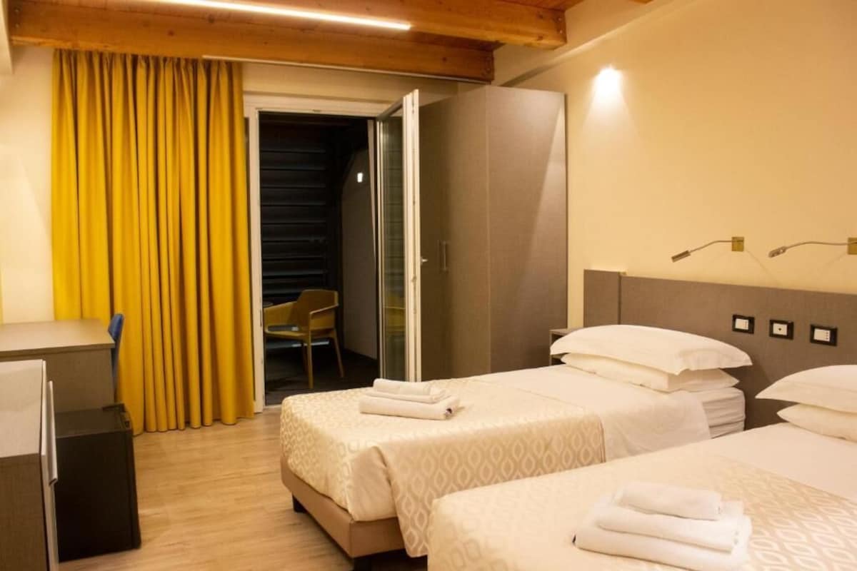 Une chambre d’hôtel avec deux lits, un bureau et une armoire.