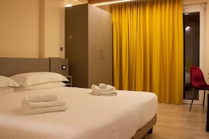 Une chambre d’hôtel avec un lit, une armoire, une chaise et un rideau.