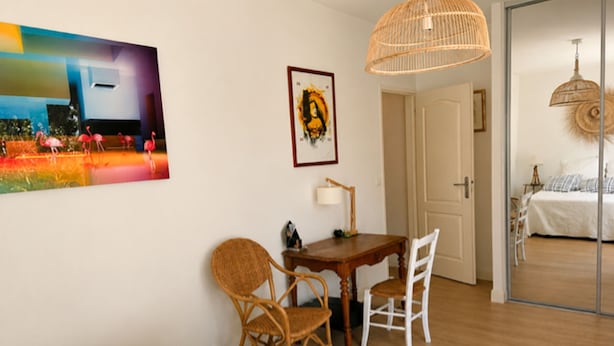 Una stanza con un letto, un tavolo da pranzo con sedie, una lampada e un quadro appeso al muro.