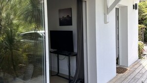 Una stanza con una porta scorrevole in vetro che dà su un balcone, un tavolino e una televisione a parete.