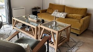 Un soggiorno con un tavolino da caffè in vetro, un divano color senape e un tappeto decorato.