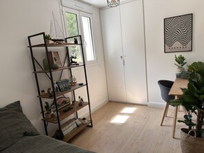 A room with a bed, a bookshelf, a desk, a chair, a door, and a window. - Cozy apartment near the beach - 5 guests (La Teste-de-Buch)
