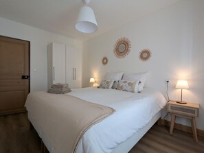 Ein Schlafzimmer mit Bett, Nachttischen, einem Kleiderschrank und Wanddekoration.