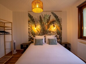Ein Schlafzimmer mit einem großen Bett, einem Holzkopfstück, Wandmalerei, zwei Nachttischlampen und einem Fenster.