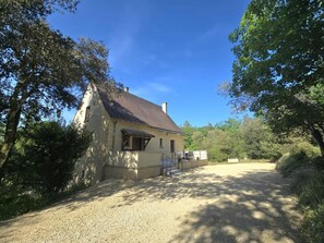 A single-story house with a gravel driveway, surrounded by trees. - Forest house, pets and parking - 8 guests (Les Eyzies)