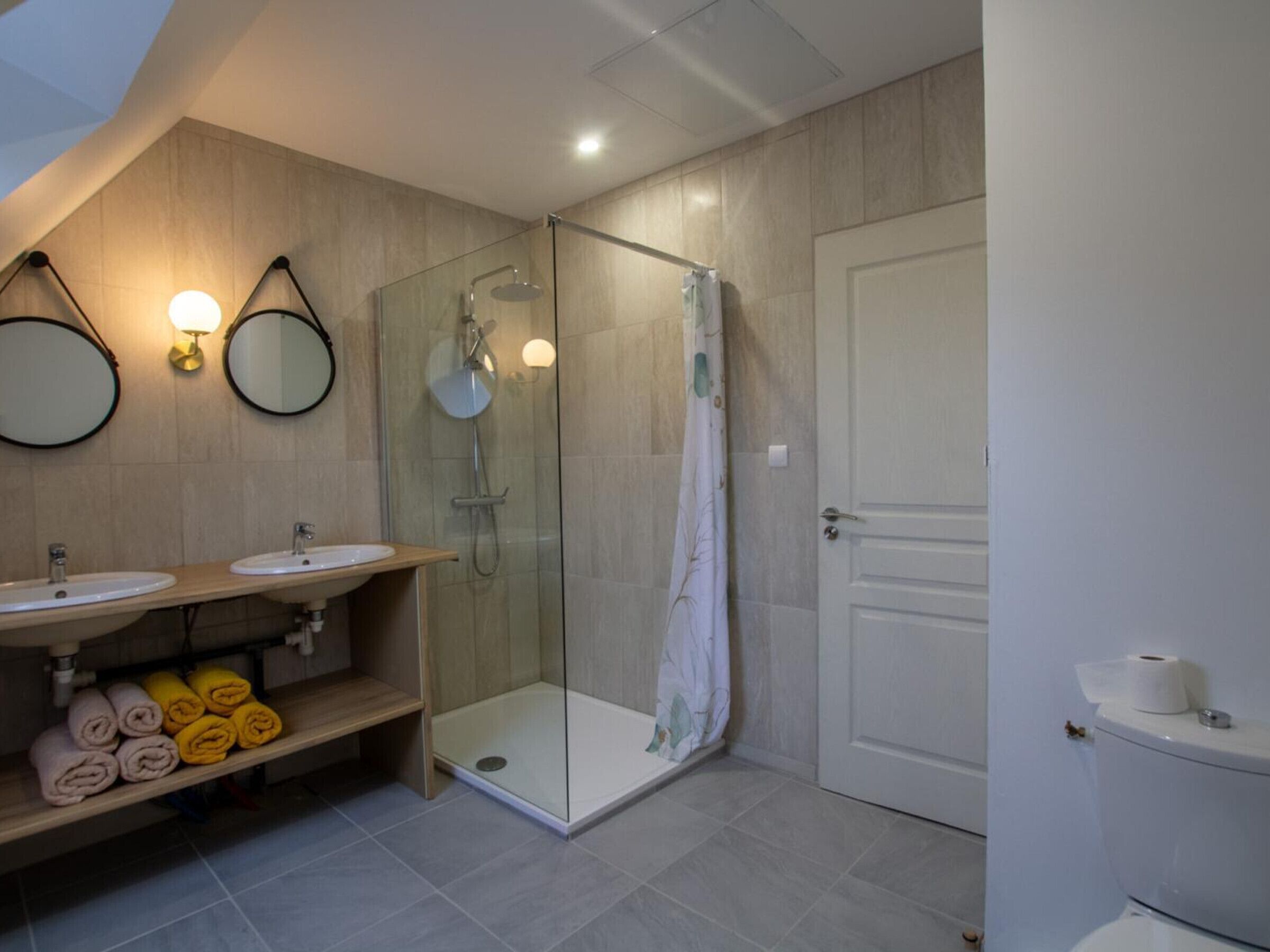 Un baño moderno con dos lavamanos, una ducha con paredes de cristal y un inodoro.