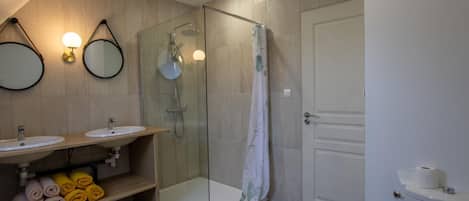 Un baño moderno con dos lavamanos, una ducha con paredes de cristal y un inodoro.