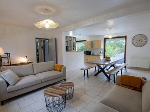 A modern living room with a sofa, coffee table, and dining table. - Forest house, pets and parking - 8 guests (Les Eyzies)