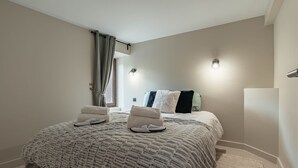 A bedroom with a large bed, two bedside tables, a window with curtains, and a wall-mounted light fixture. - Tranquil apartment - 4 guests (Les Belleville)