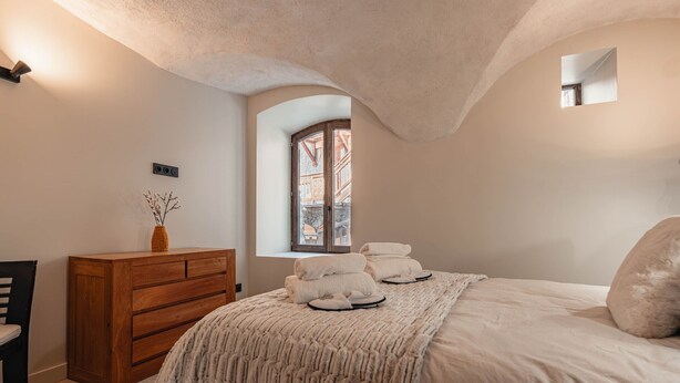 A bedroom with a bed, a wooden dresser, a window, and a mirror. - Tranquil apartment - 4 guests (Les Belleville)