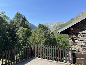 A stone building with a wooden fence in front, surrounded by trees and mountains in the background. - Tranquil apartment - 4 guests (Les Belleville)