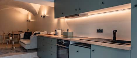 Una cocina moderna con electrodomésticos integrados, un comedor con mesa y sillas, y una zona de estar acogedora.