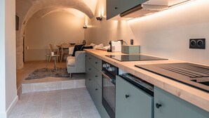 A modern kitchen with a built-in stove, a dining area with a table and chairs, and a cozy seating area with a sofa. - Tranquil apartment - 4 guests (Les Belleville)