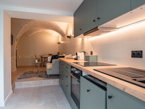 Eine moderne Küche mit eingebautem Herd, ein Essbereich mit Tisch und Stühlen sowie eine gemütliche Sitzecke mit einer Couch.