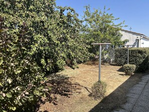 A garden with a metal structure, dry grass, and a building in the background. - Spacious and tranquil house - 5 guests (Givrand)