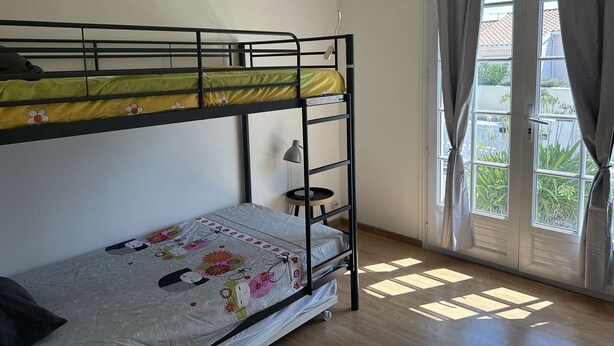 Ein Zimmer mit einem Etagenbett, einem Schreibtisch, einer Lampe und einem Fenster mit Vorhängen.