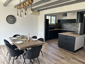 Uma cozinha moderna com armários pretos, uma mesa de jantar de madeira e um relógio preto na parede.