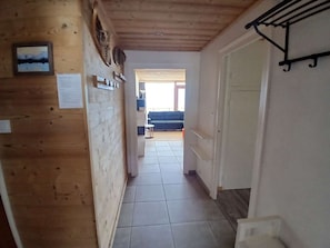 Ein Korridor mit Holzwänden, einem Fliesenboden und einer Tür zu einem Raum mit einem blauen Sofa.