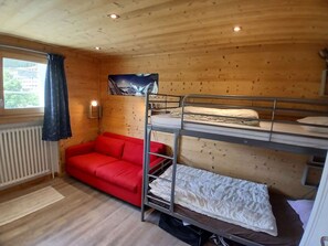 A compact room with bunk beds, a red sofa, a radiator, and a window with curtains. - Apartment in Vieil Alpe - 6 guests (Huez)