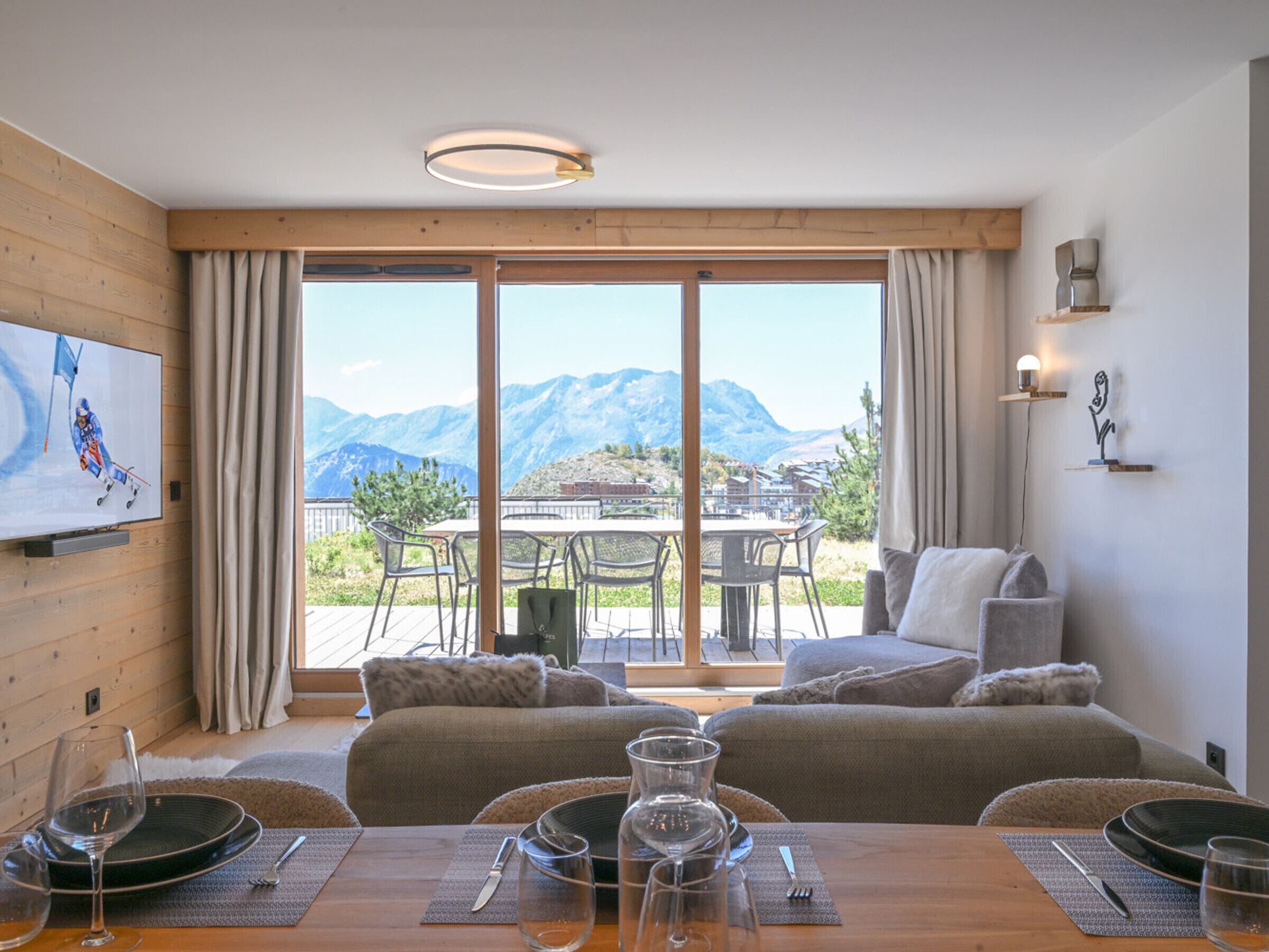 A room with a dining area, a sofa, and a view of mountains.