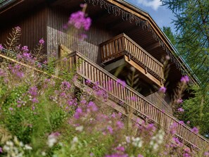 Eine Holzhütte mit einem Balkon, umgeben von Wildblumen.