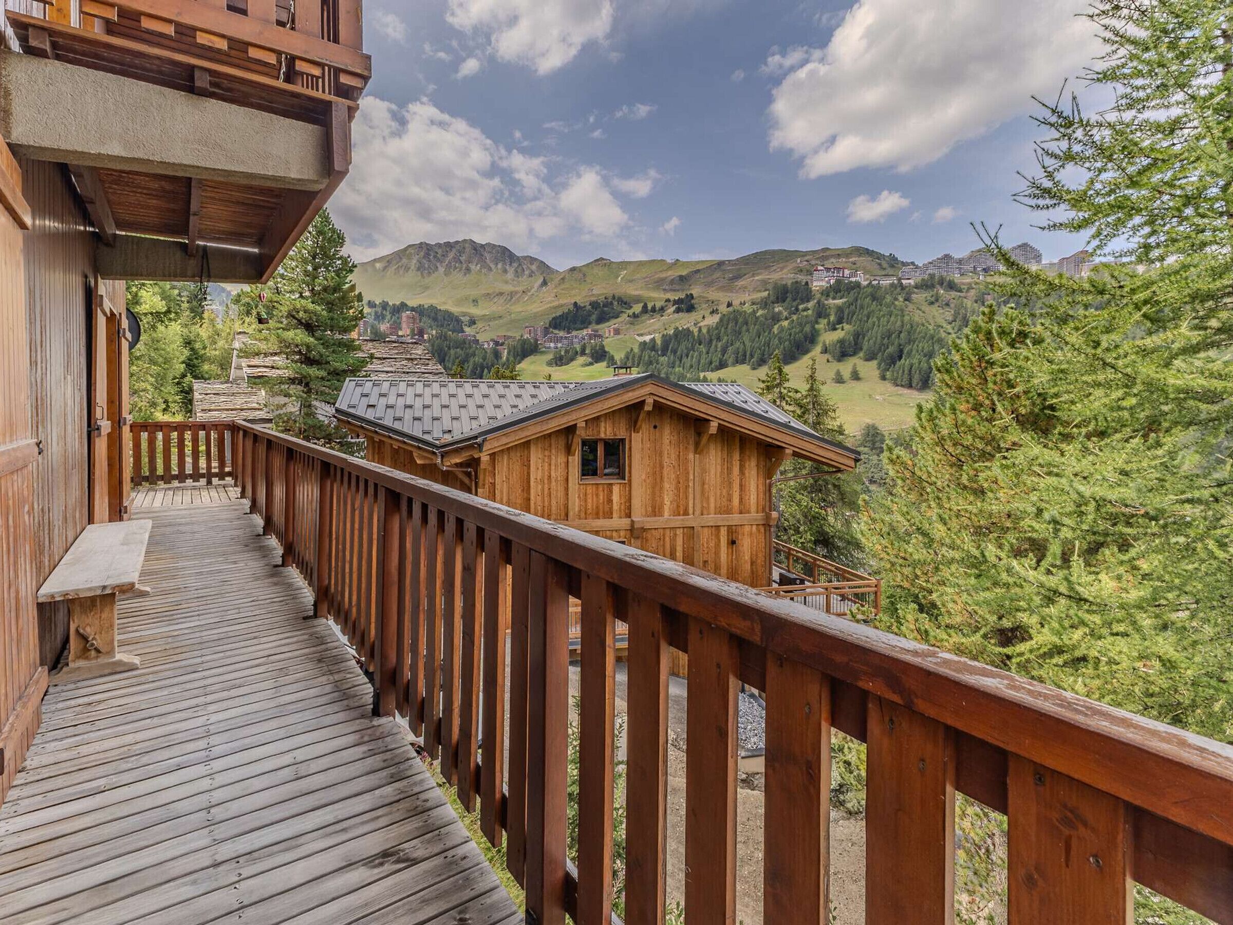A wooden deck leading to a chalet with a mountain view.