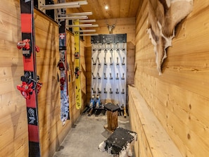 A ski lodge interior with wooden walls, a mounted deer head, ski racks, and a sled. - Chalet with panoramic view - 14 guests (La Plagne 1800)