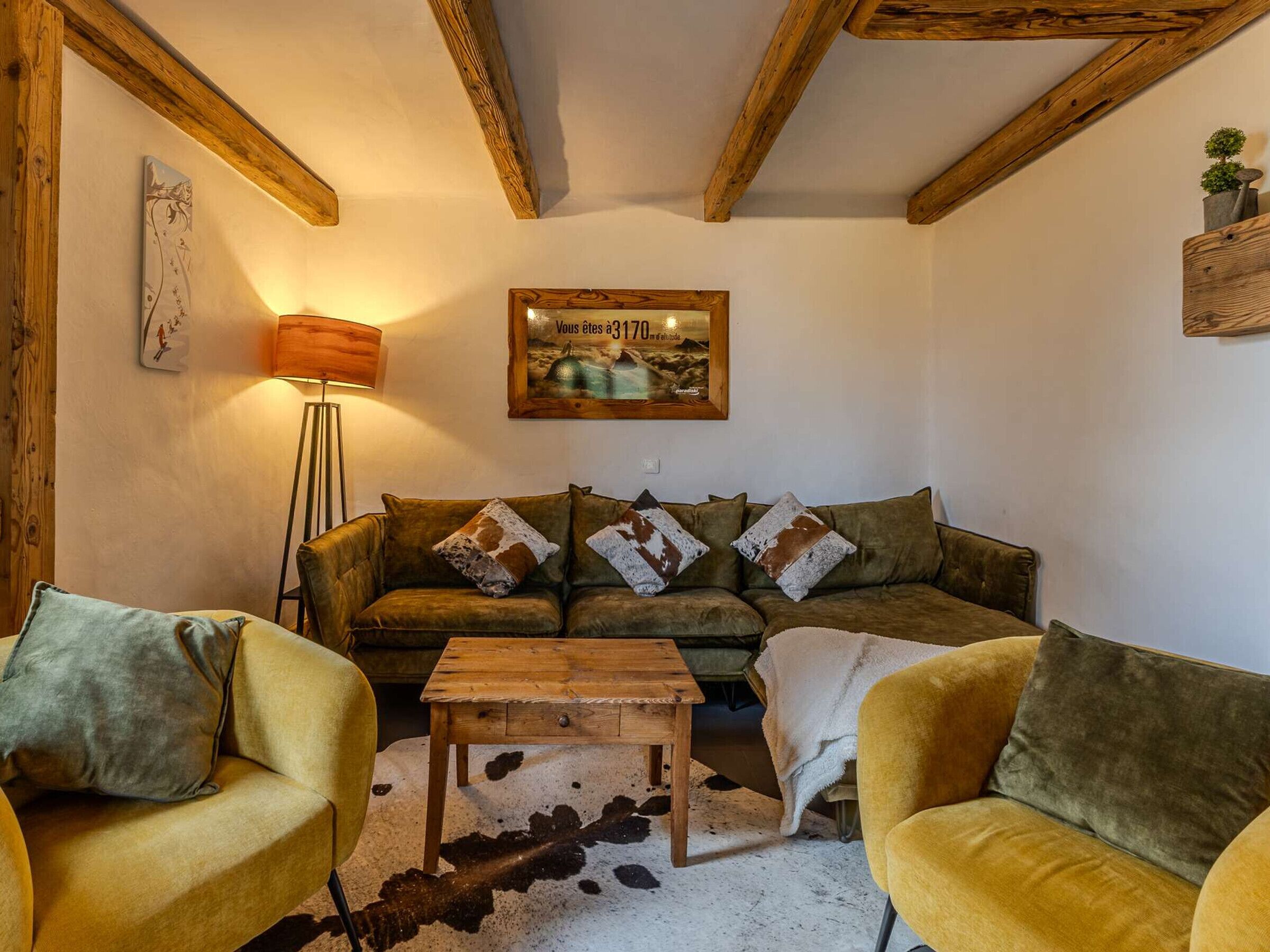A cozy living room with a sofa, two armchairs, a coffee table, and a painting on the wall.