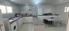 A compact kitchen with a washing machine, a microwave, and a small dining table. - 2-Bedroom Apartment in Downtown Rabat (Rabat)