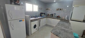 A compact kitchen with a built-in washing machine, a gas stove, and a refrigerator. - 2-Bedroom Apartment in Downtown Rabat (Rabat)