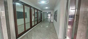 A corridor with a tiled floor, glass doors, and a fire extinguisher on the wall. - 2-Bedroom Apartment in Downtown Rabat (Rabat)