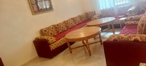 A living room with a sofa, two round wooden tables, and patterned cushions. - 2-Bedroom Apartment in Downtown Rabat (Rabat)