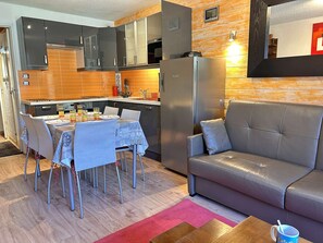 A modern kitchen with a dining area, a refrigerator, and a leather sofa. - Apartment with piste view - 5 guests (Risoul)