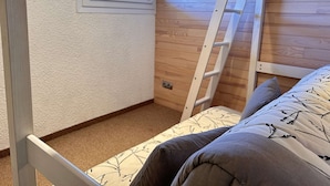 Ein Stockbett mit einer Leiter, einem Fenster und einem farbenfrohen Bild an der Wand.