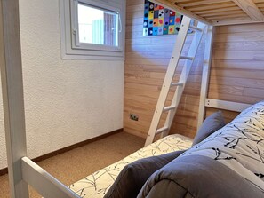 Ein Stockbett mit einer Leiter, einem Fenster und einem farbenfrohen Bild an der Wand.