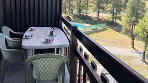 Ein Balkon mit Tisch, Stühlen und Blick auf eine bewaldete Landschaft.